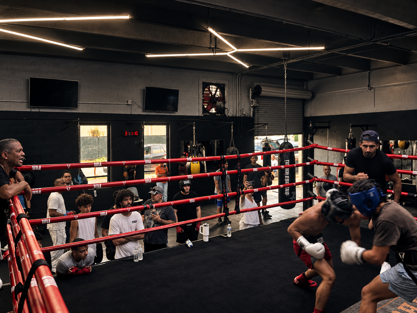 Fighters sparring, watched by the academy from ringside